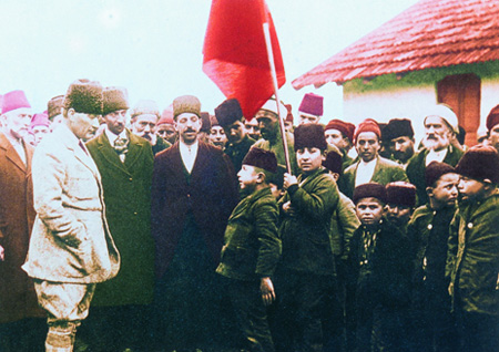 Atatürk Türk bayrağı yanında bir topluluğu selamlarken